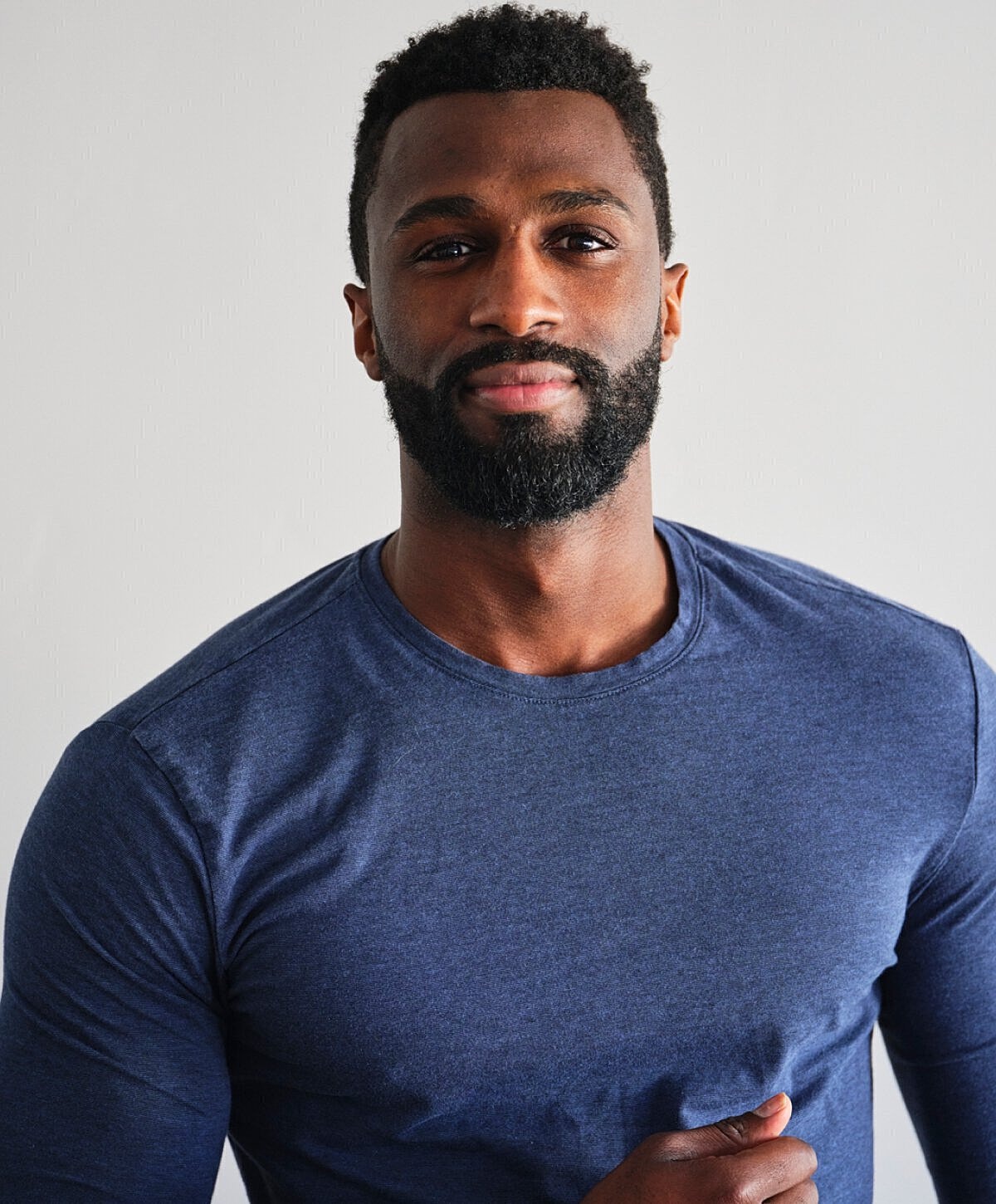 Shirtless man by the water, holding a bottle.