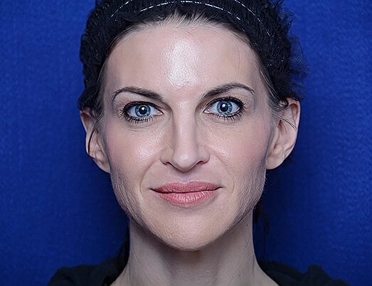 Woman with blue eyes against blue background.