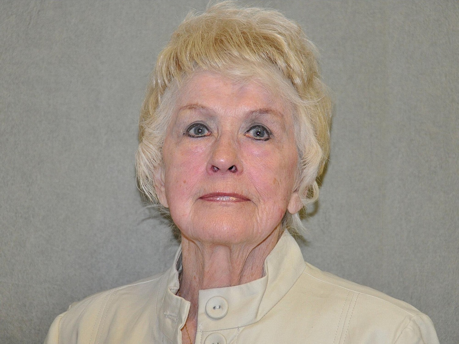 Elderly woman with light hair and neutral expression.