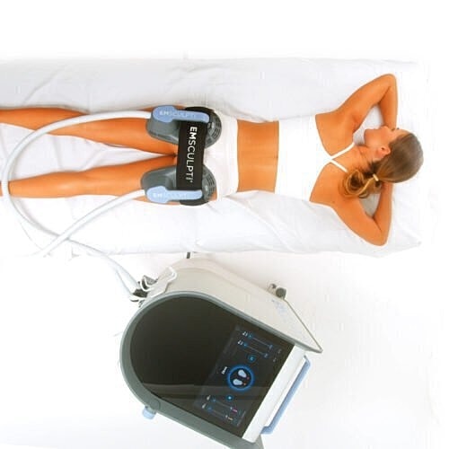 Woman undergoing body sculpting treatment with machines.