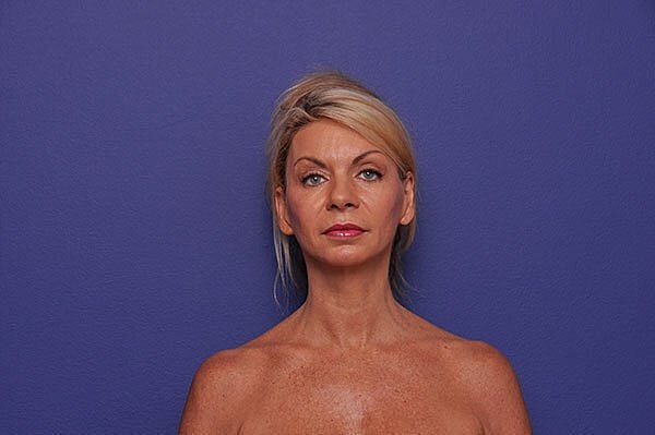 Woman with blonde hair against purple background.