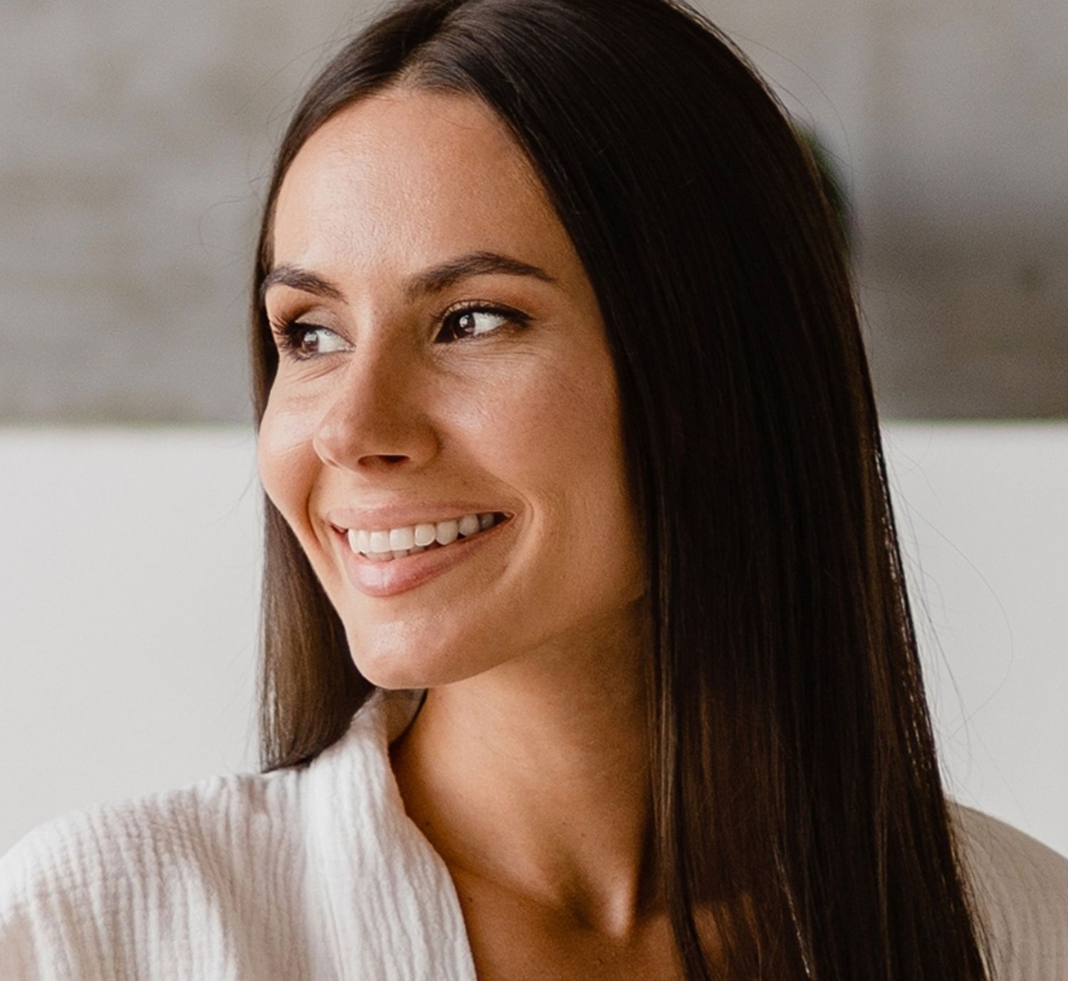 Smiling woman in a floral dress and wide hat.
