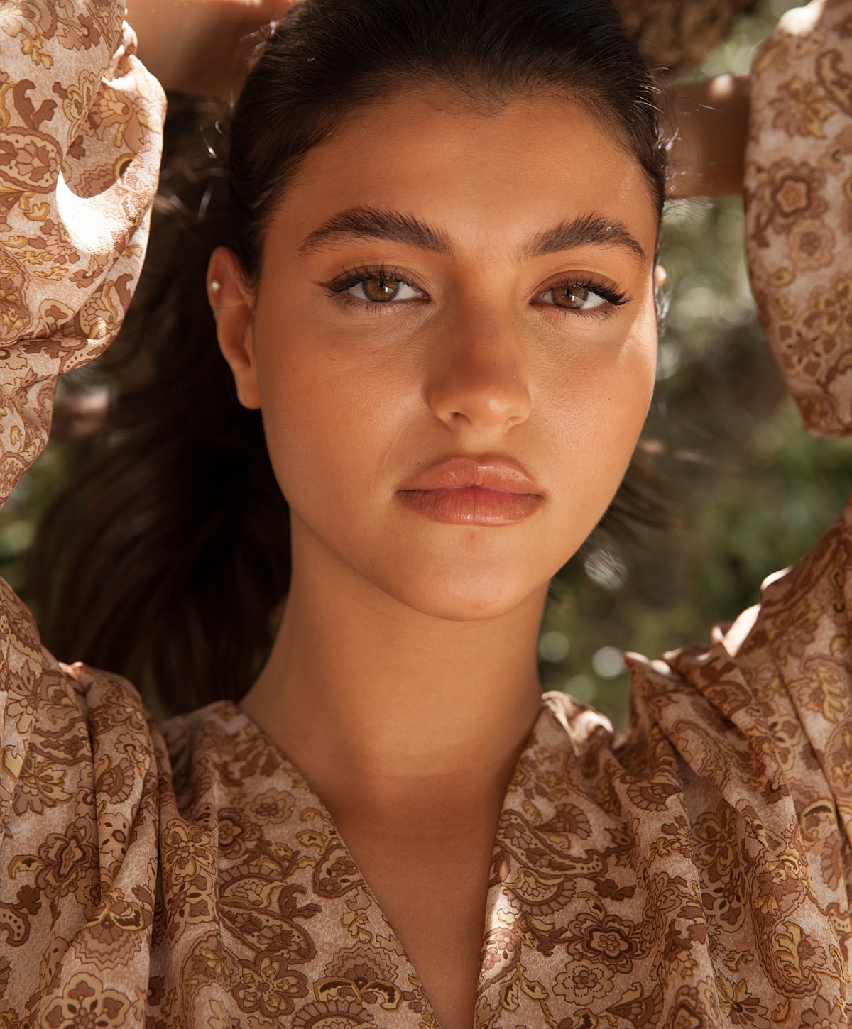 Young woman with long hair and floral blouse.