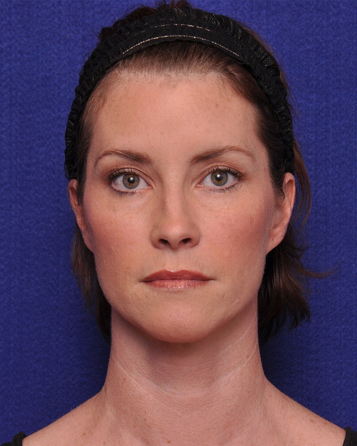 Smiling woman in stylish dress, arms crossed.