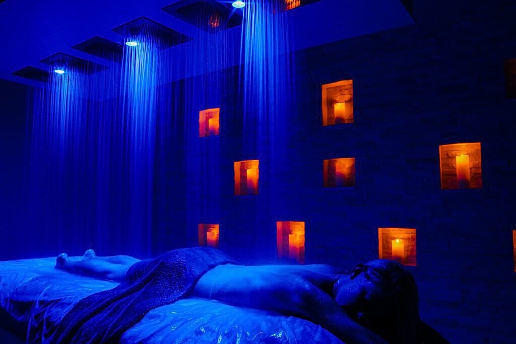 Relaxing spa scene with blue lighting and candles.