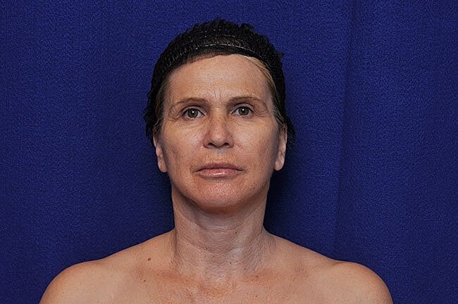 Woman with minimal makeup against a blue background.