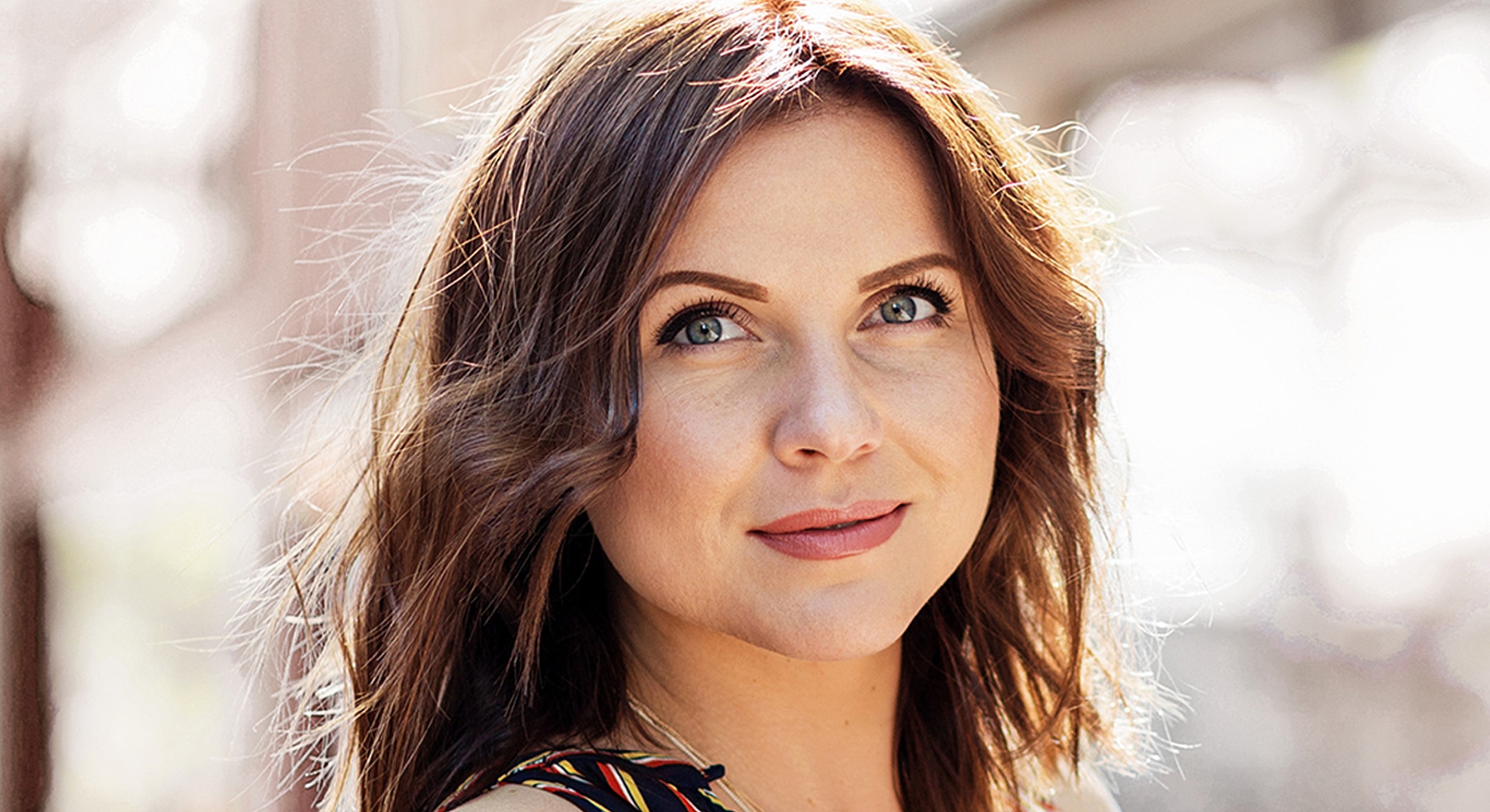 Smiling woman with wavy hair outdoors.